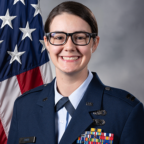 Smiling person in U.S. Air Force uniform with an American flag behind them